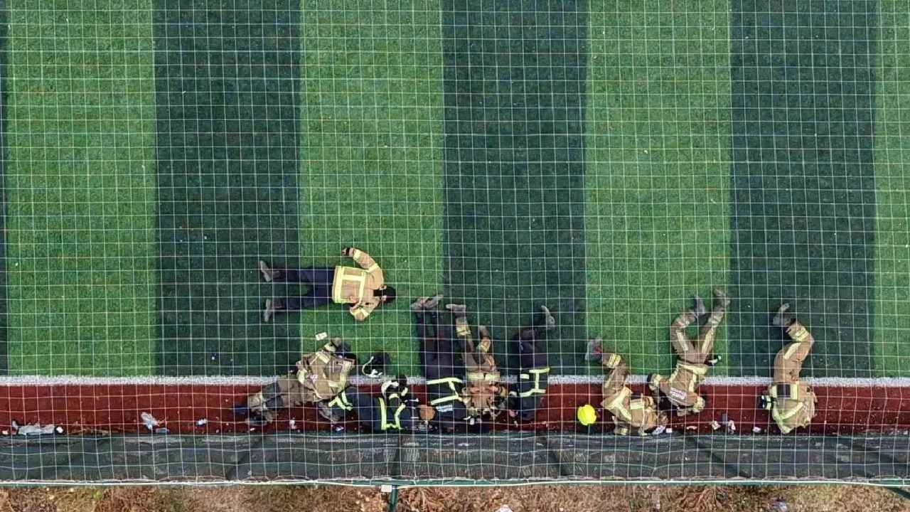 Feuerwehrleute, die gegen die Flammen kämpften, ruhten sich auf dem Kunstrasenplatz aus